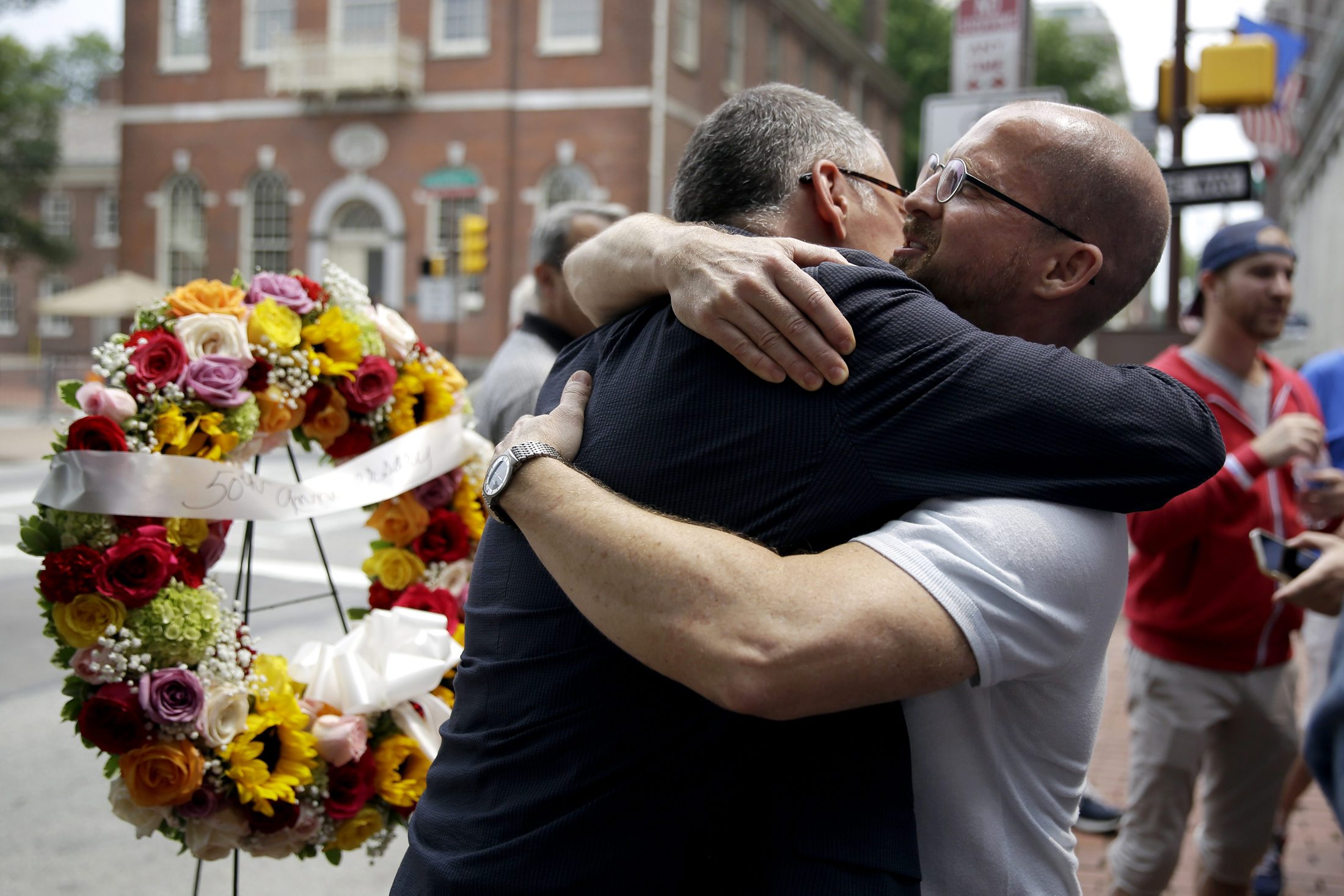 Jim Obergefell, left, the man behind the landmark Supreme Court gay marriage ruling, hugs Jeff Sigler, of New York, after laying a wreath at the Gay Pioneers historical marker across from Independence Hall and the Liberty Bell Center, Thursday, July 2, 2015, in Philadelphia. Some 40 activists picketed for gay rights on July Fourth in 1965 at the site. (AP Photo/Matt Slocum)